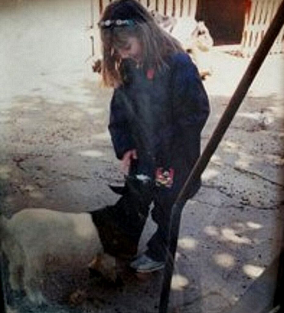 Laia acariciando un animal en una granja mostrando su pasión temprana por los animales Veterinaria de fauna salvaje desde la infancia